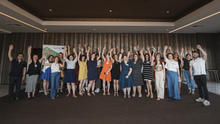 Group of people standing before a wall and raising theirs hands